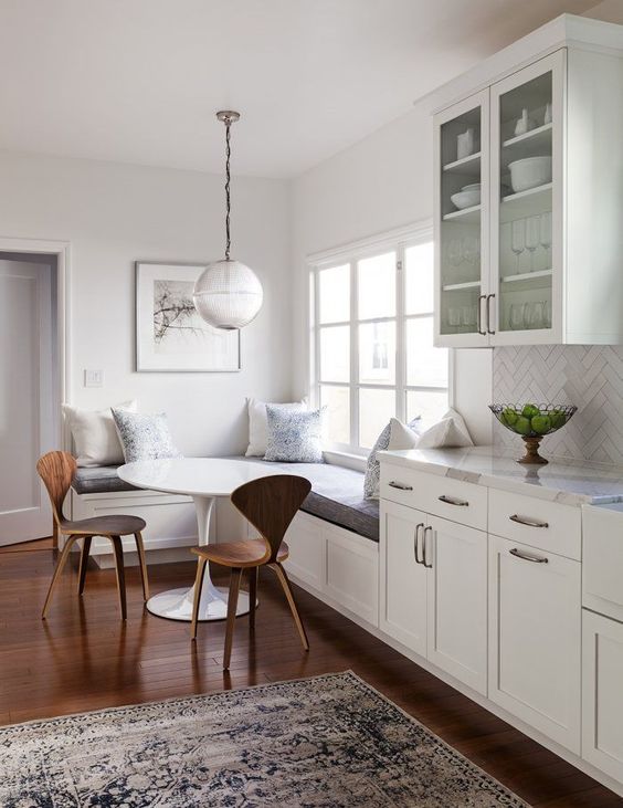 white dining area and kitchen // Globus pendant light // wooden floors // corner bench // white cupboards