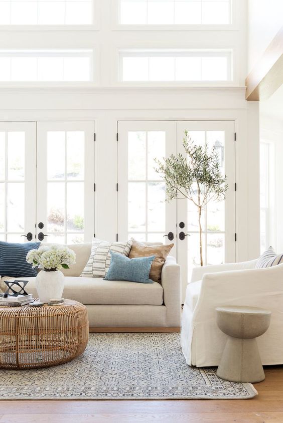 bright white cozy living room // daylight // French doors // while sofa // white armchair // wicker coffee table