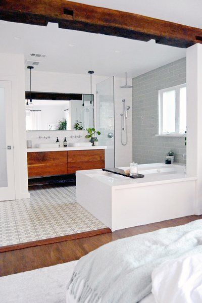 A bathtub and a large, reclaimed beam (recovered from an old barn) form a casual boundary between the bathroom and bedroom. Moroccan-inspired cement tiles, a custom-made washstand, Kohler bathroom fittings made of white quartz create a spa feeling. Photo 3 of 9 in the Spenla Master Bed & Bath Open Space concept