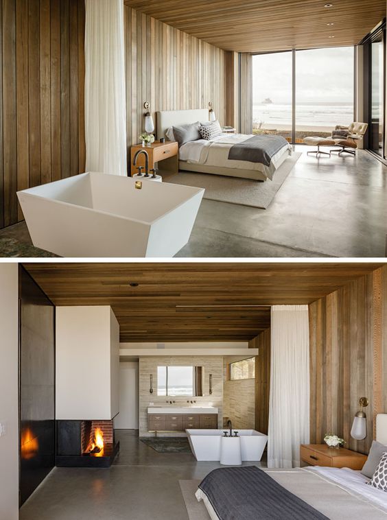 Wooden walls have been installed in this modern master bedroom to match the wooden ceiling, while leaving the private bathroom open so you can see the water from the bathtub. #MasterBedroom #WoodWalls #WoodCeiling #OpenBathroom #Fireplace
