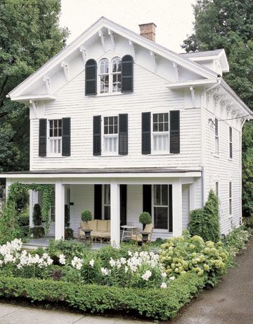 Classic white house with black shutters and big front porch .