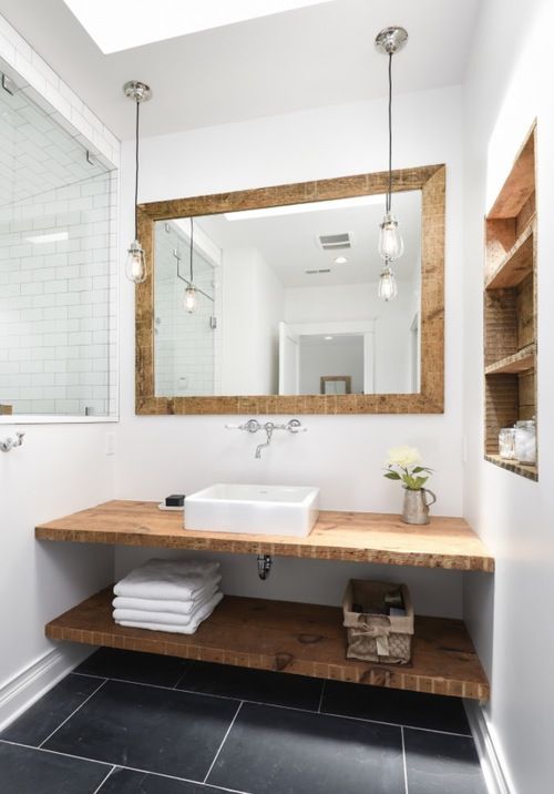 White bathroom with black tile and wooden accents .