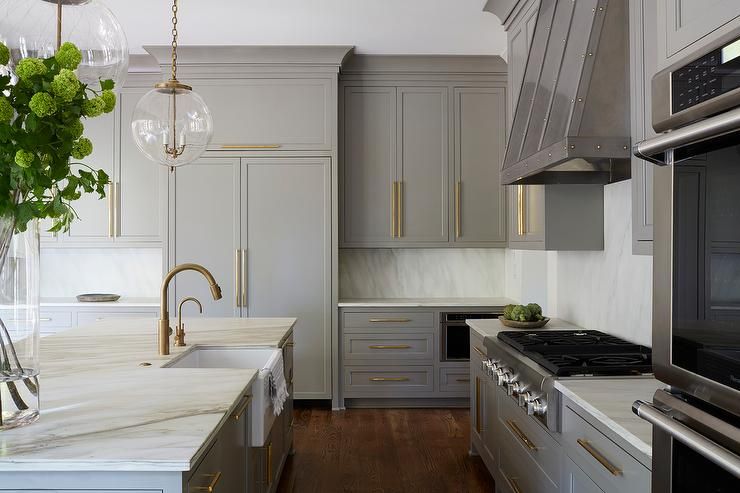 Gold and gray kitchen features creamy gray cabinets adorned with .